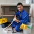 cheerful asian plumber sitting floor repairing kitchen sink 1098 17780