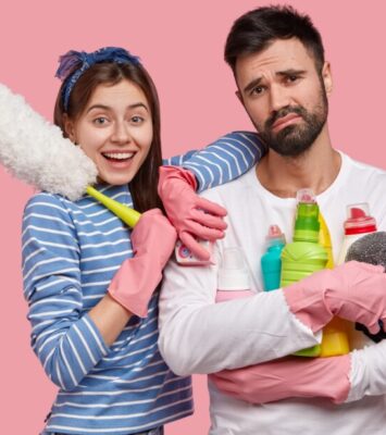 glad attractive woman has toothy smile leans shoulder handsome displeased man holds brush 1