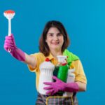 middle aged woman wearing apron rubber gloves holding cleaning supplies scrubbing brush 1